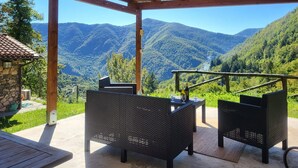A covered outdoor seating area with wicker furniture, a stone building, and a view of mountains. - Borgo Mulino,unique setting, private pool,  mountain views WIFI, walk restaurant (Vallico Sopra)