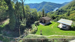 A stone building with a small patio, surrounded by lush greenery and mountains in the background. - Borgo Mulino,unique setting, private pool,  mountain views WIFI, walk restaurant (Vallico Sopra)