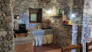 A rustic stone kitchen with a sink, wooden cabinets, and a rustic wooden chair. - Borgo Mulino,unique setting, private pool,  mountain views WIFI, walk restaurant (Vallico Sopra)