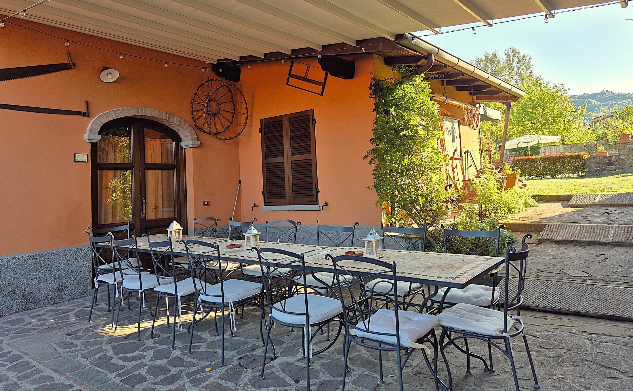 Un patio al aire libre con una mesa y sillas, un reloj y vistas a zonas verdes y colinas.