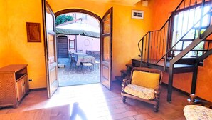 Un interior con una escalera, un comedor con mesas y sillas, y un mueble de madera.