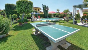 Un espacio exterior bien cuidado con mesa de ping-pong, piscina y diferentes zonas de estar.
