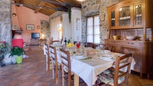 Un coin repas rustique avec des murs en pierre, des poutres en bois et une table dressée pour le repas.