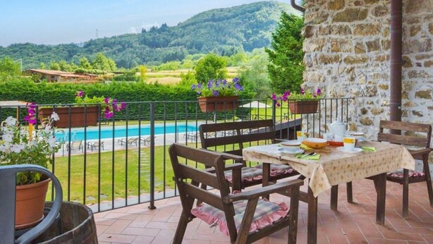 Une terrasse avec une piscine, un mur en pierre et des sièges d’extérieur.