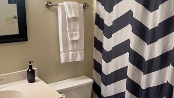 Un baño con inodoro, lavamanos y cortina de ducha.