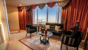 A modern living room with a sofa, two armchairs, a coffee table, and a view of a cityscape through large windows. - Holiday Villa Hail Hotel (Ha'il)