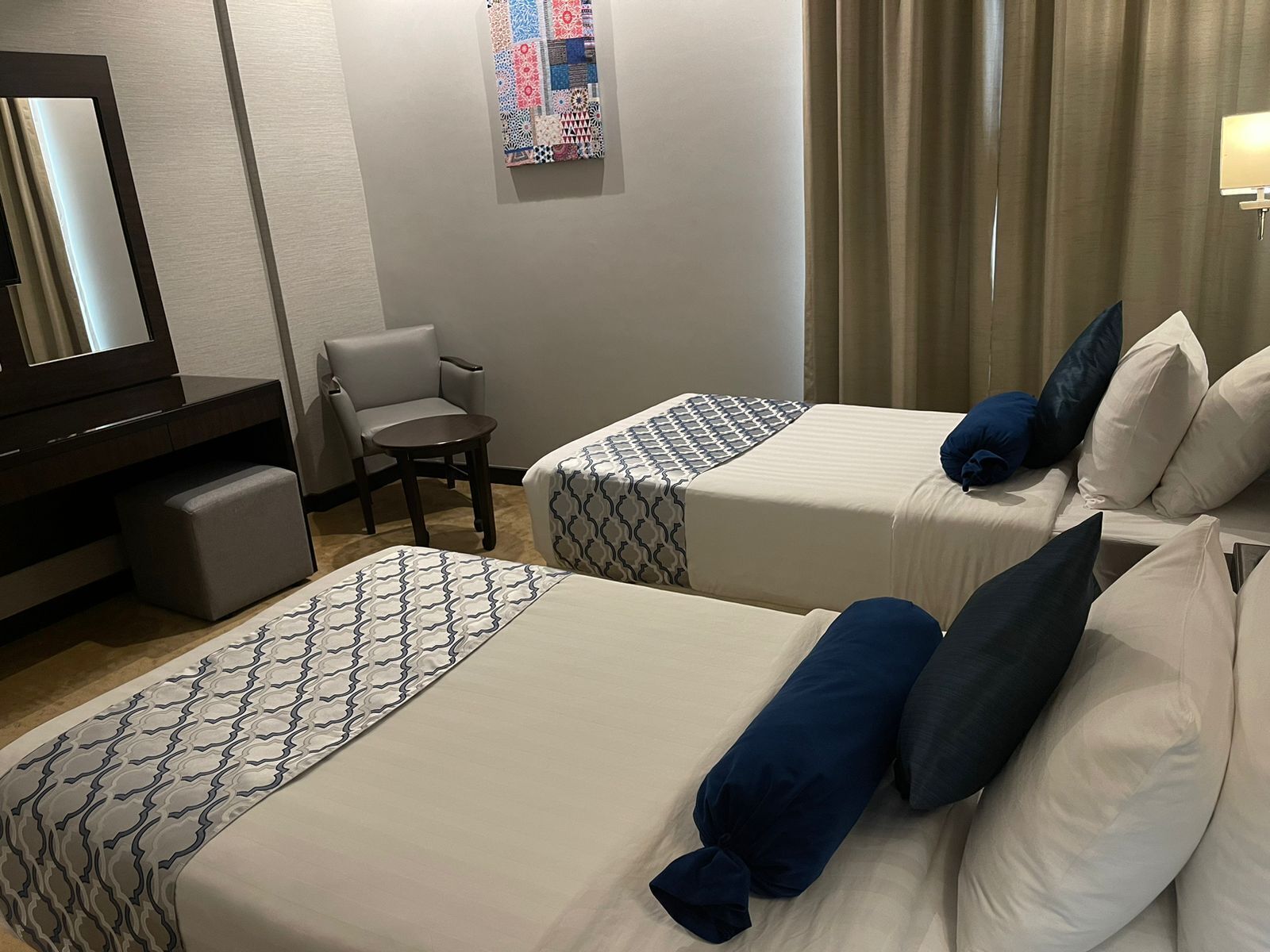 Une chambre d’hôtel avec deux lits, une chaise, un bureau et un miroir.