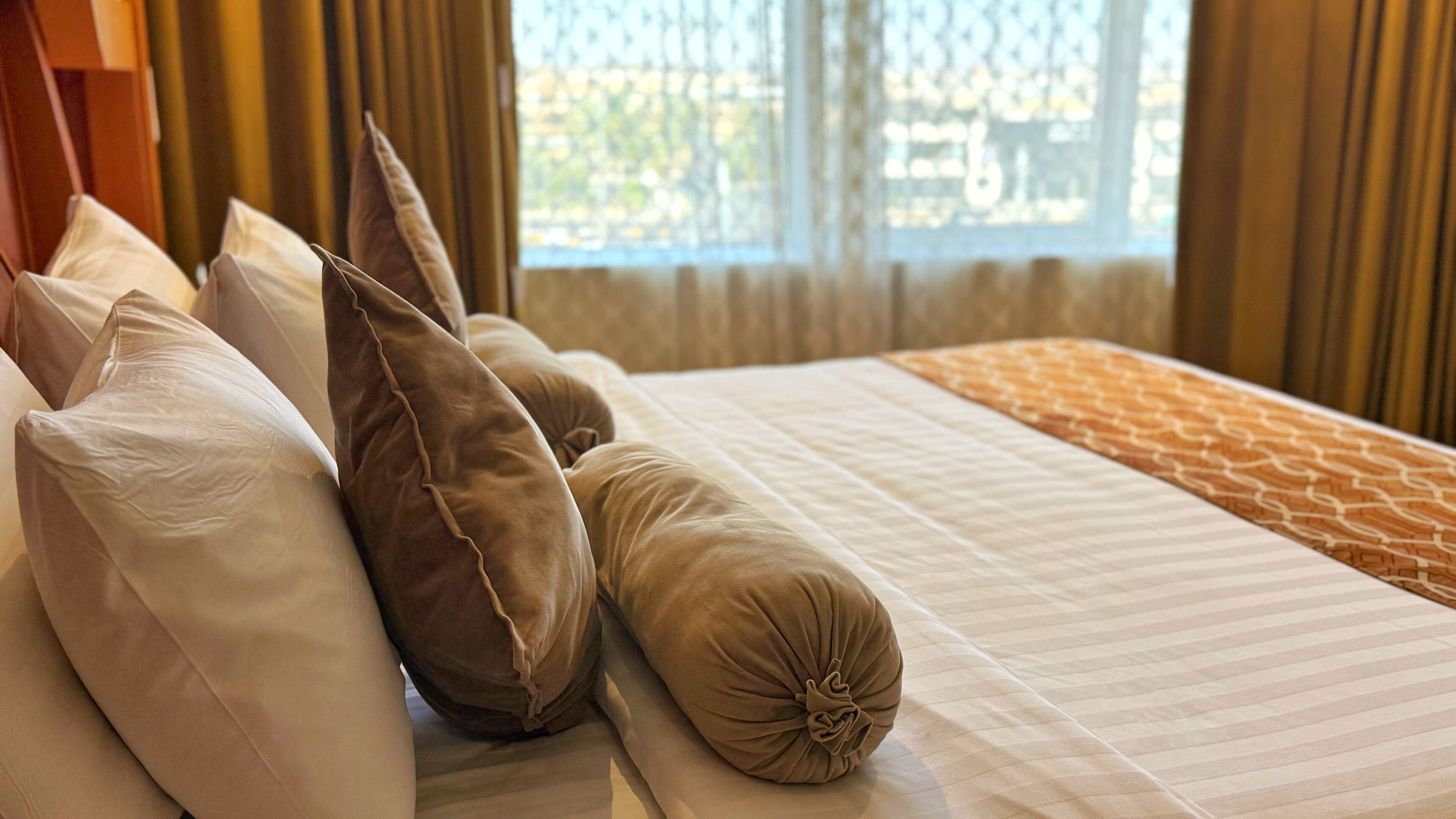A neatly made bed with a striped bedspread and multiple pillows, including a decorative one.