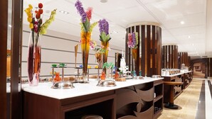 A buffet area with multiple serving stations, each with a variety of dishes and colorful floral centerpieces. - Holiday Villa Hail Hotel (Ha'il)