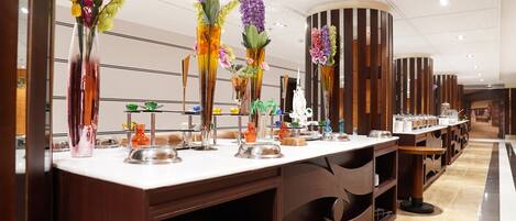 A buffet area with multiple serving stations, each with a variety of dishes and colorful floral centerpieces.