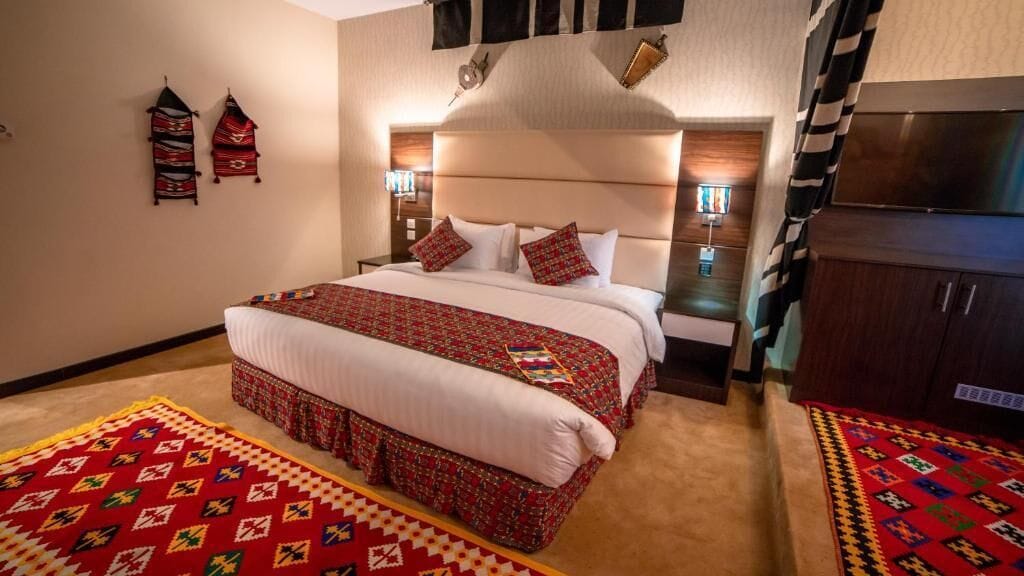 A hotel room with a large bed, two bedside tables, a TV, and a wardrobe.