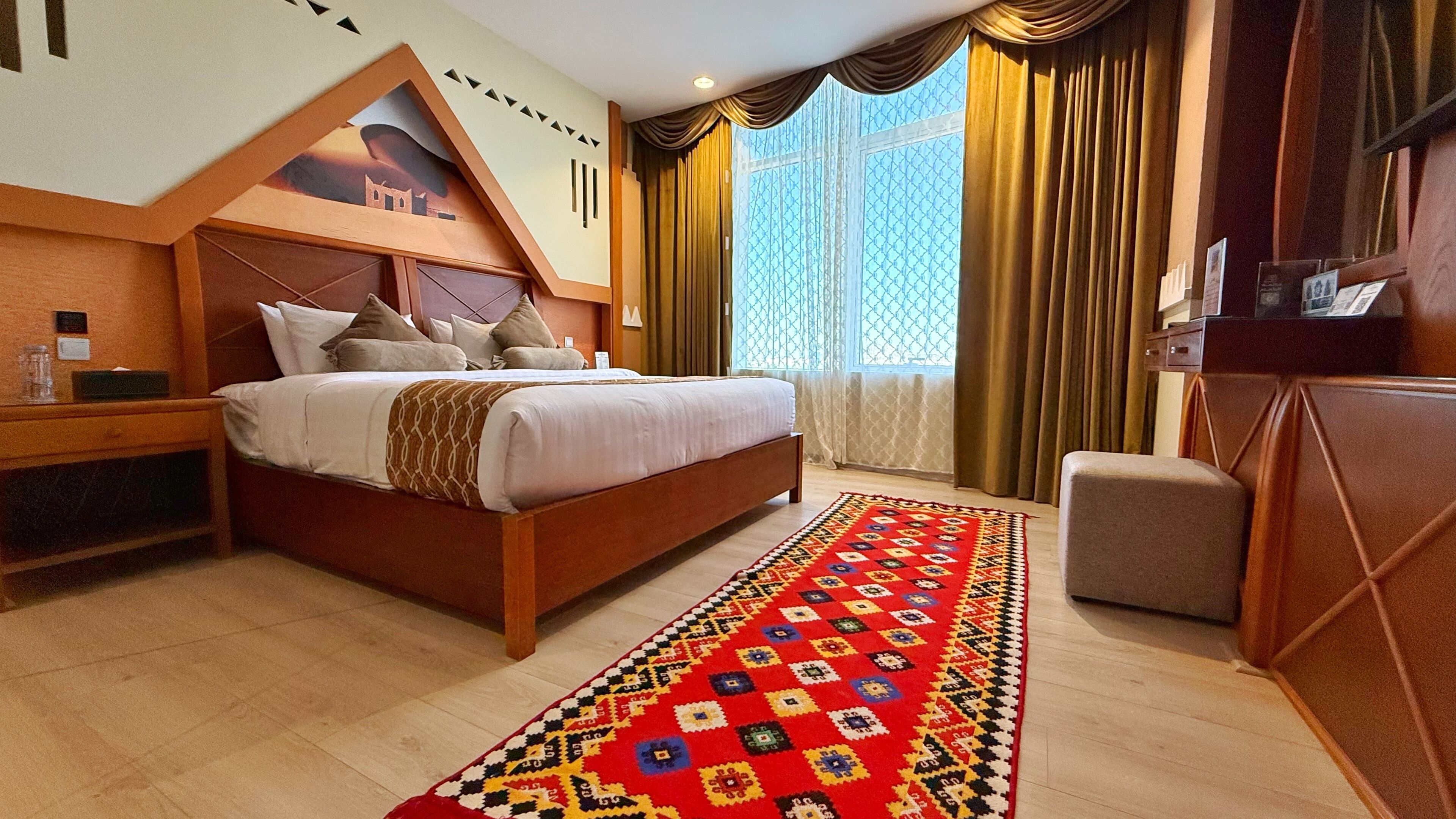 Una habitación de hotel con una cama grande, una mesita de noche, un escritorio y un televisor.