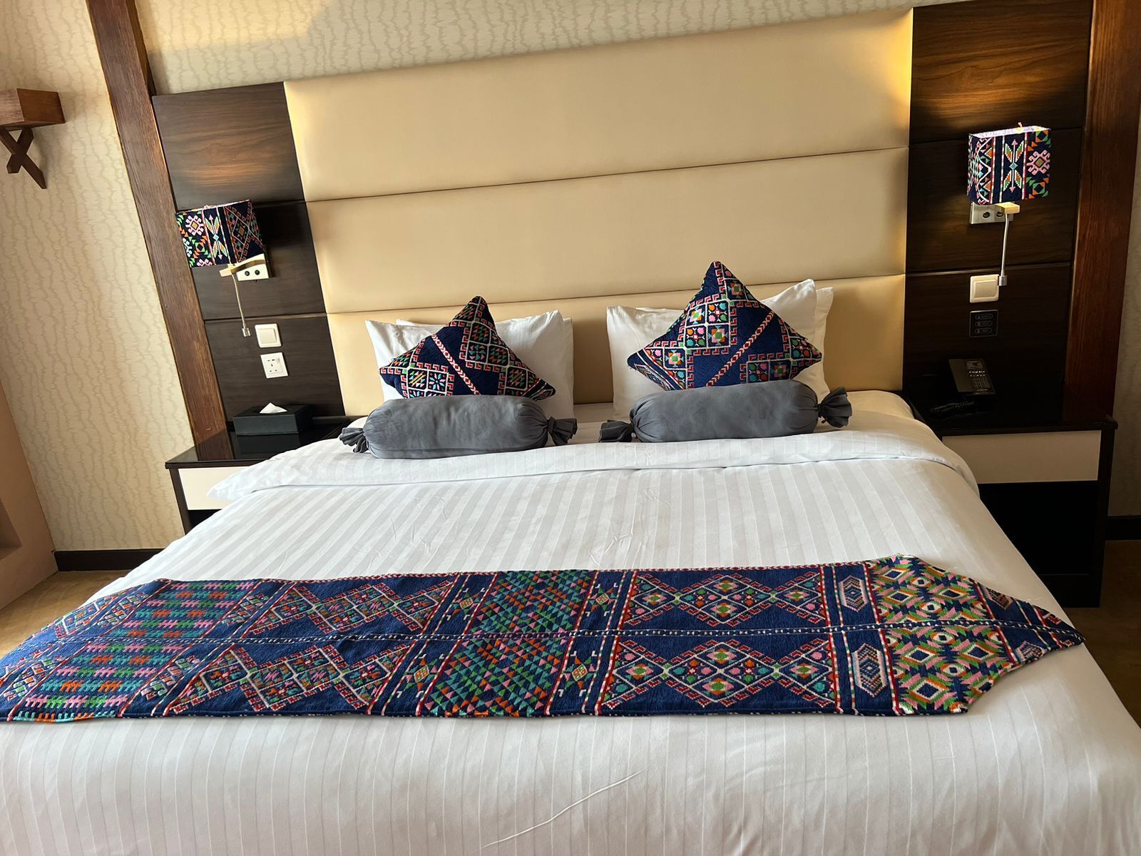 Una habitación de hotel con una cama grande, dos mesitas de noche y una lámpara de pared.