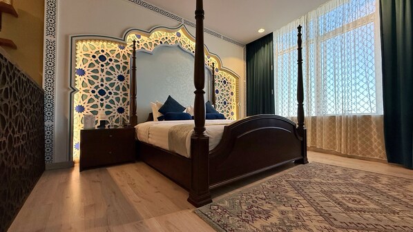 A four-poster bed with a nightstand, a patterned wall, and a large window with curtains. - Holiday Villa Hail Hotel (Ha'il)