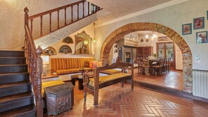 A staircase leading to a living area with a sofa, wooden bench, and a dining table with chairs. - Home Cinema • Private Pool & Hot Tub • Sleeps 12 (6 Bathrooms) (Pergine)