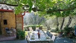 An outdoor dining area with a table set for four, surrounded by chairs, under a tree. - Home Cinema • Private Pool & Hot Tub • Sleeps 12 (6 Bathrooms) (Pergine)