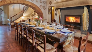 A dining room with a long table set for a meal, a fireplace, and a staircase leading to an upper level. - Home Cinema • Private Pool & Hot Tub • Sleeps 12 (6 Bathrooms) (Pergine)