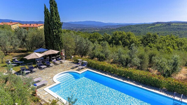 A swimming pool with lounge chairs and umbrellas, surrounded by greenery and mountains in the background. - Home Cinema • Private Pool & Hot Tub • Sleeps 12 (6 Bathrooms) (Pergine)