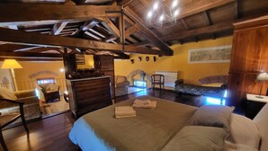 A cozy room with a large bed, wooden furniture, and a high ceiling with exposed beams.