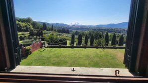A view from a balcony with a clear sky, a green lawn, and distant mountains.