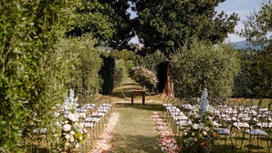 An outdoor wedding aisle with white chairs and floral decorations.