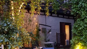 A courtyard with a paved pathway, potted plants, and a building with a sign. - Adler Gaststube Hotel Biergarten (Bad Rappenau)