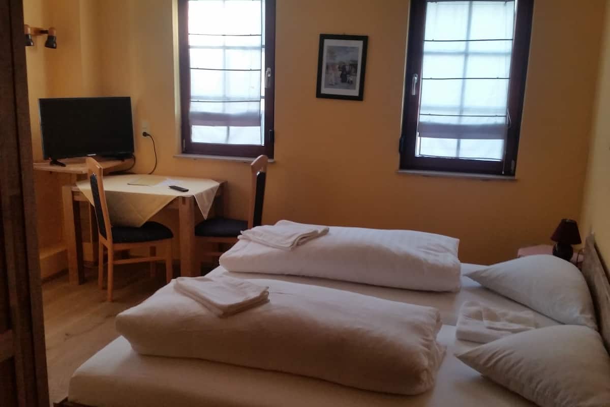 A room with two beds, a desk, and a chair.