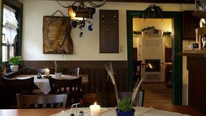 A cozy dining area with a wooden table set for two, a candle, and a potted plant. - Adler Gaststube Hotel Biergarten (Bad Rappenau)