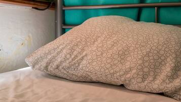 A bunk bed with a patterned pillow and a teal curtain.