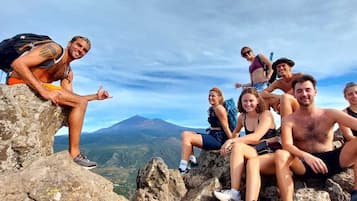 A group of people sitting on rocky terrain with a mountain in the background.
