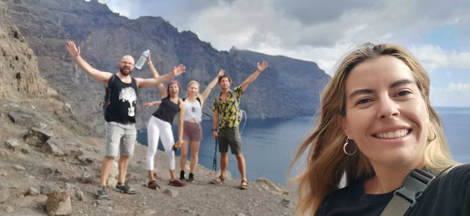 A group of people standing on a rocky cliff with a mountainous backdrop.