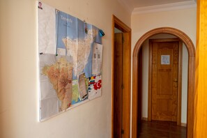 A hallway with a map on the wall and a wooden door at the end. - Arena Nest Hostel (Santiago del Teide)