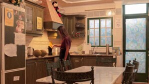 A kitchen with a dining table and chairs, a refrigerator, and a window with a view. - Arena Nest Hostel (Santiago del Teide)