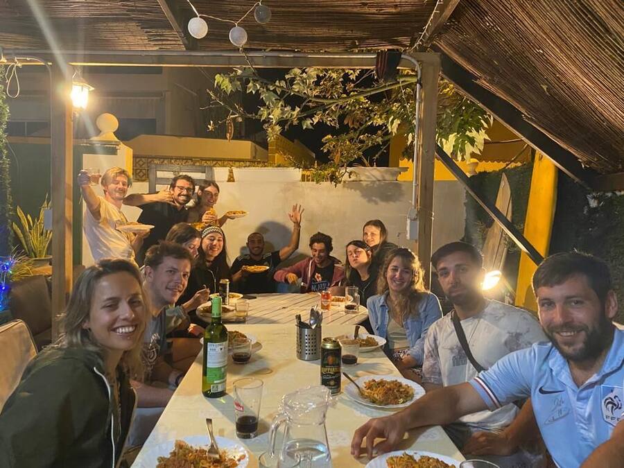 A group of people dining at an outdoor table with a variety of dishes and drinks.