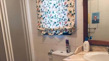 Un baño con dos inodoros, un bidé, un lavamanos y una zona de ducha.