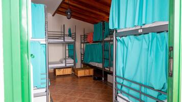 Un dormitorio con literas, un armario de madera y suelo de baldosas.