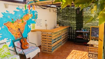 Un área de estar al aire libre acogedora con un banco de madera, una guitarra y un mapa en la pared.