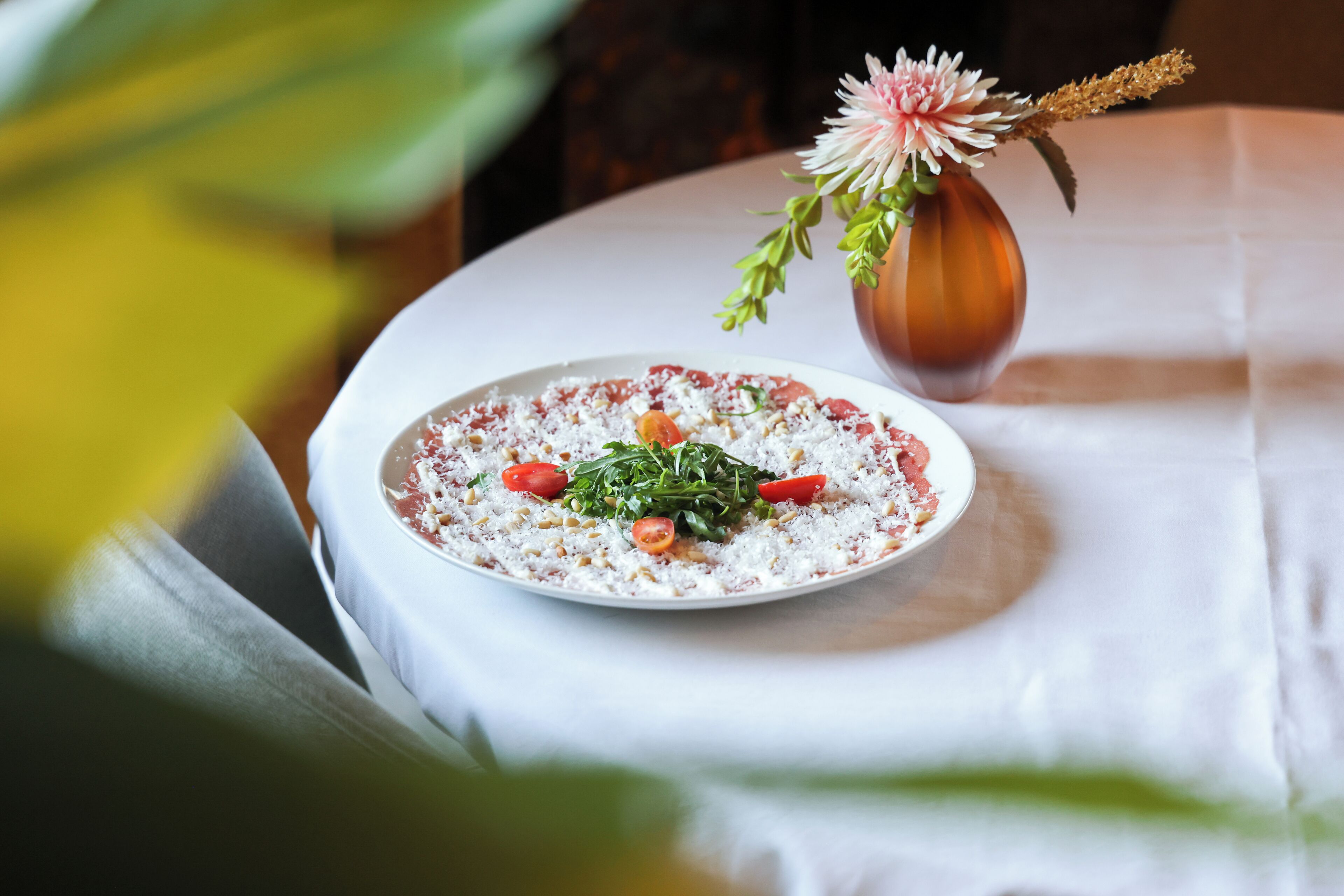 A plate of food on a table with a vase of flowers.
