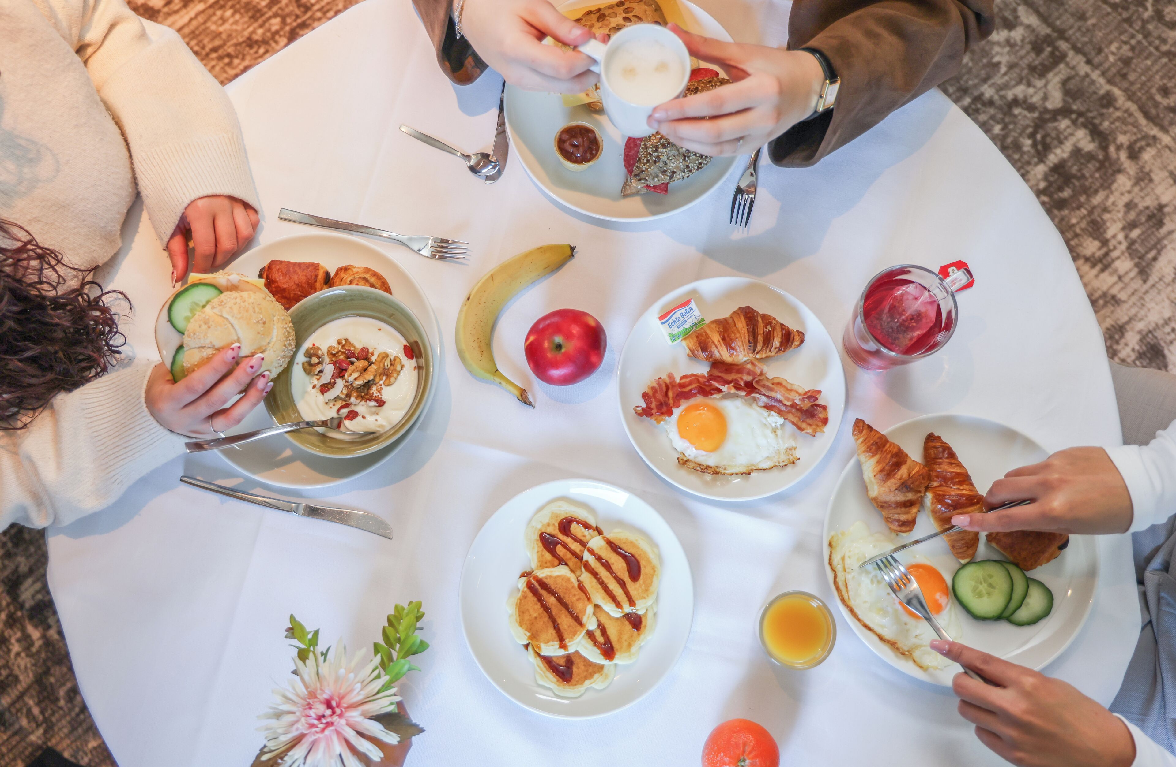 A group of people seated around a round table with breakfast items.