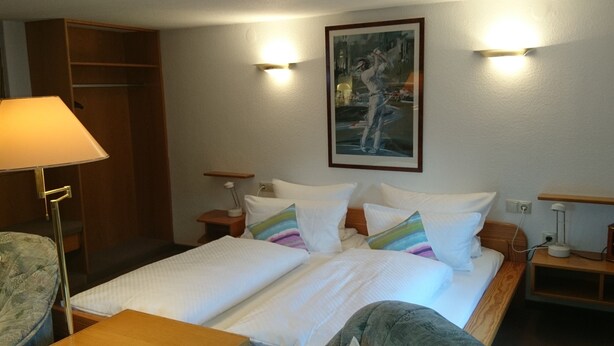 A hotel room with a bed, bedside tables, a lamp, a chair, and a painting on the wall. - Pension Landhaus Fischer (Massweiler)