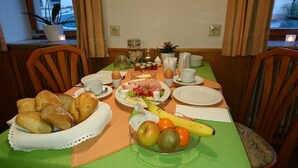 A dining table set with breakfast items including bread, fruits, cheese, and ham. - Pension Landhaus Fischer (Massweiler)
