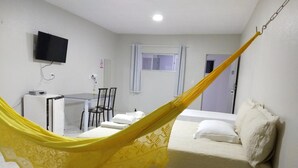 Una habitación de hotel con cama, escritorio, silla, televisor y ventana.
