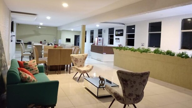 Un hall de hotel con una recepción, un comedor y un área de estar con sofás y sillones.