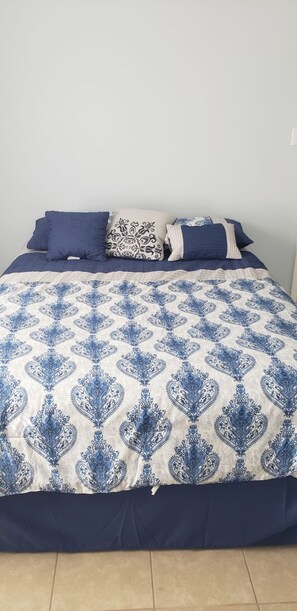 Comfortable bed with a stylish bedspread, set against a clean and well-maintained backdrop.