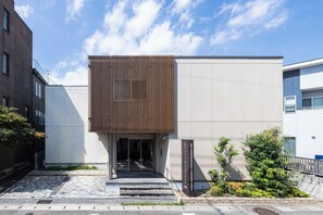 A modern building with a vertical wooden panel facade, a glass entrance, and a sign indicating 'Hotel Grand Base.' - GRAND BASE Beppueki (Beppu)