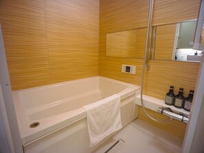Ein modernes Badezimmer mit einer weißen Badewanne, einer Dusche und einer Holzwand.