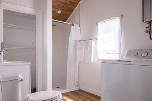 Ein kleines Badezimmer in Weiß mit Dusche, Toilette und Waschmaschine.