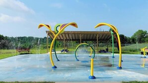 An outdoor playground with colorful climbing structures and a covered seating area.