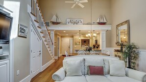 A spacious living room with a high ceiling, a staircase, a dining area, and a kitchen. - 122 Abbington is a beautiful 3-bedroom, 3 bath villa in Palmetto Dunes (Hilton Head Island)