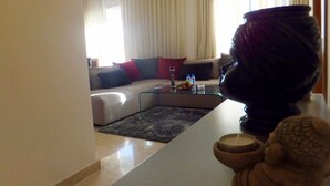 Uma sala de estar com um sofá, uma mesa de centro de vidro e um vaso decorativo.